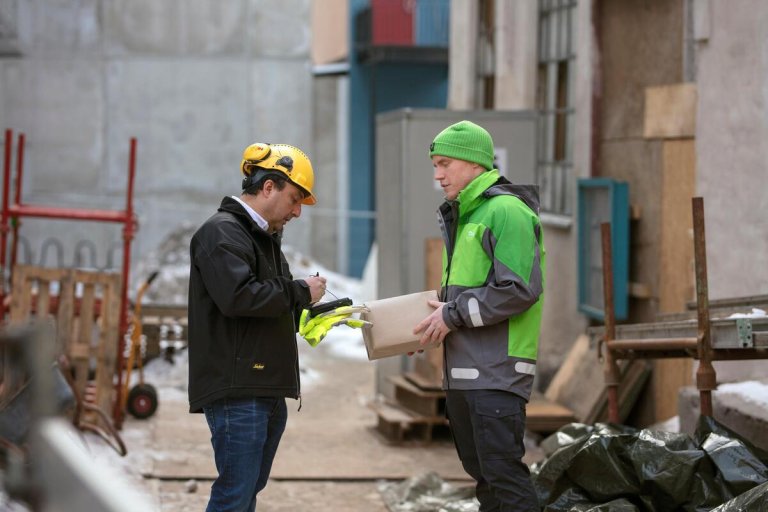 A courier delivers a package to a craftsman on a construction site