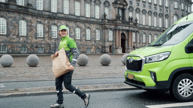A Bring driver delivers a parcel in a big city.