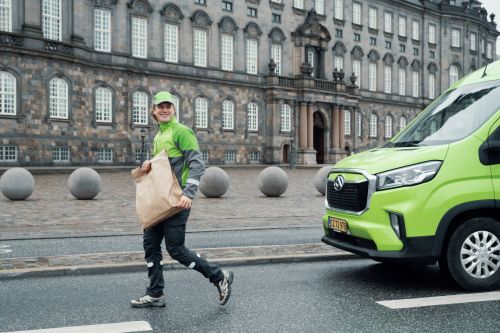 A Bring driver delivers a parcel in a big city.