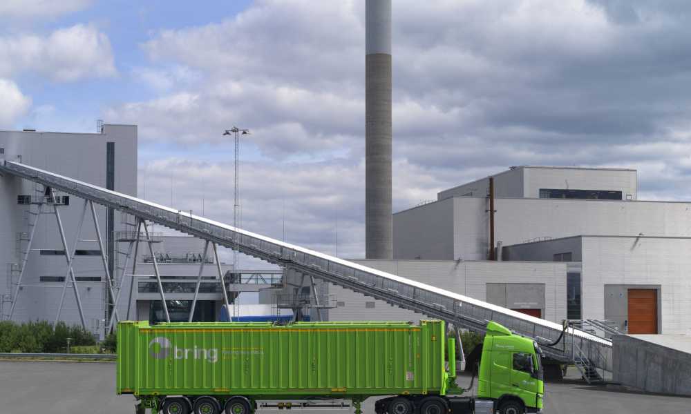 A green Bring truck standing next to a factory