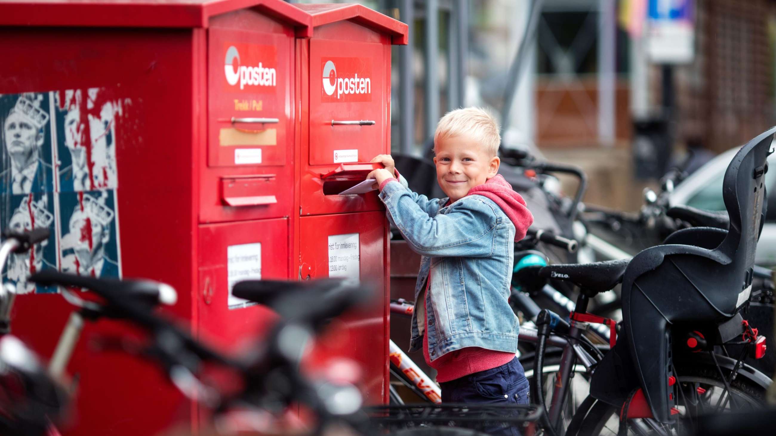 Boy putting a letter into a red postbox