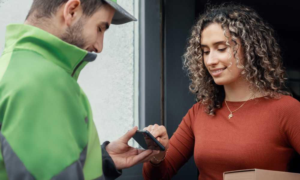 A woman signs for a home delivery from Bring on a cellphone