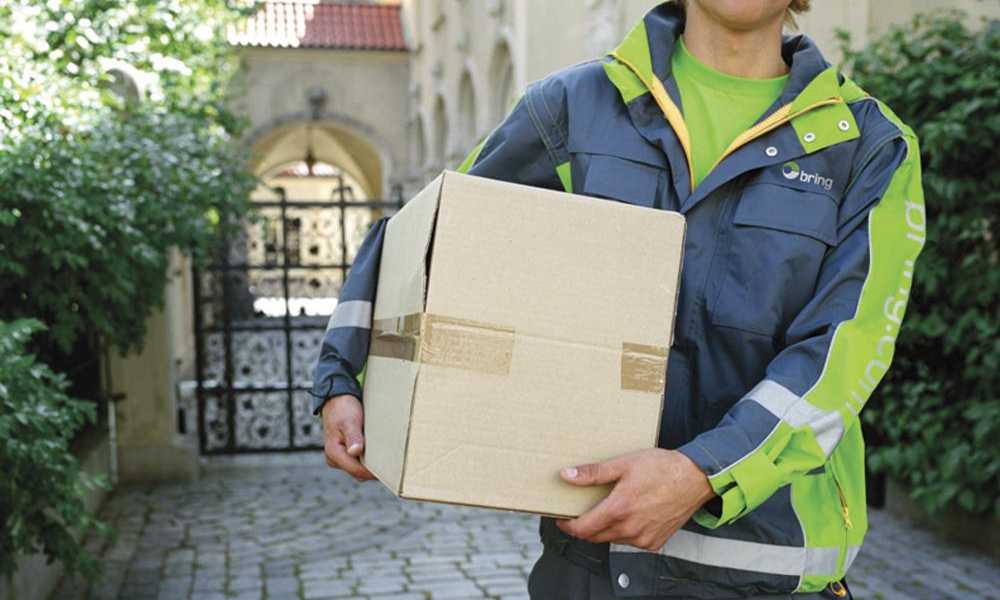 A man wearing a Bring uniform with a parcel under his arm