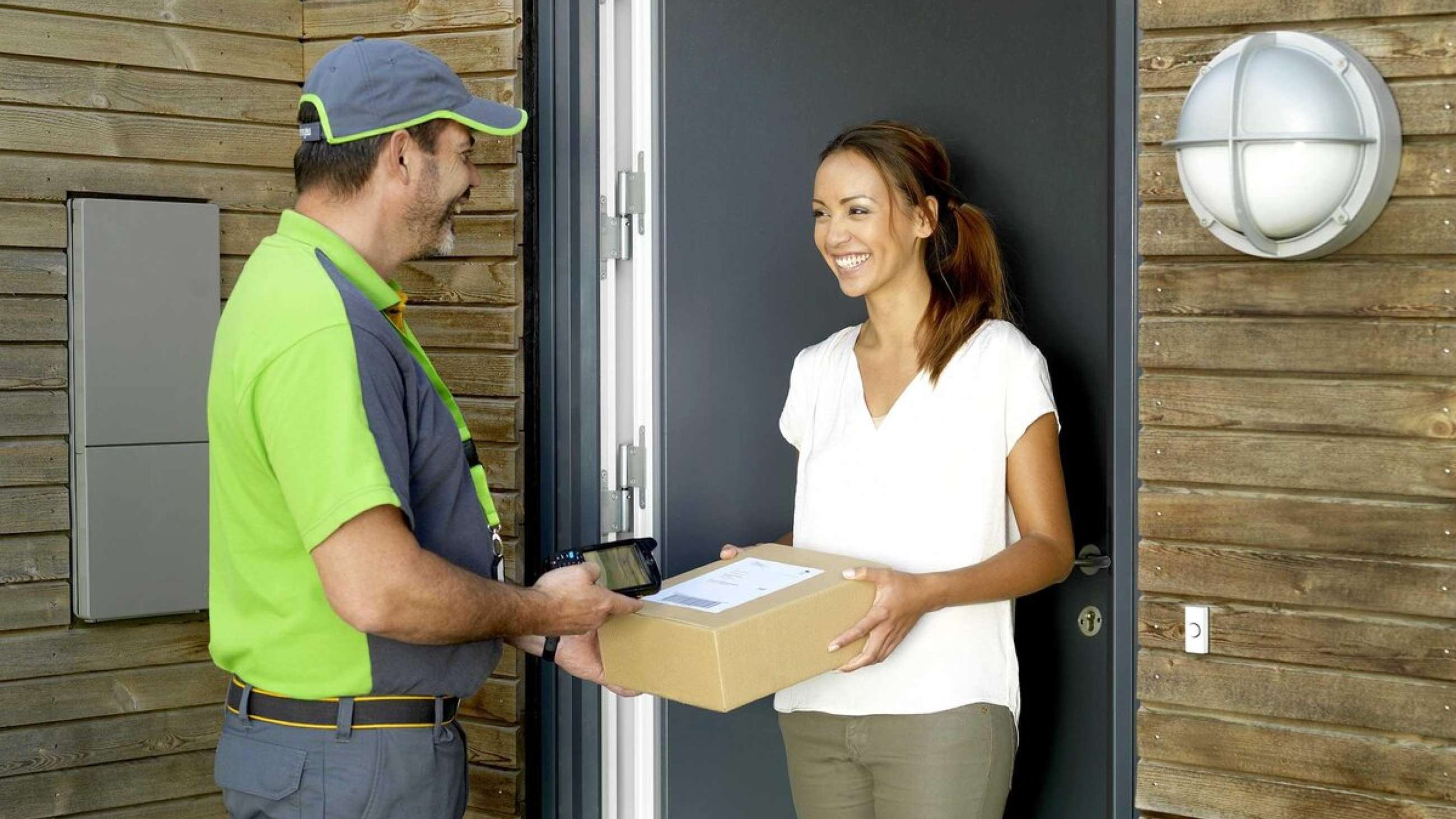 A Bring courier who delivers a parcel to a smiling person