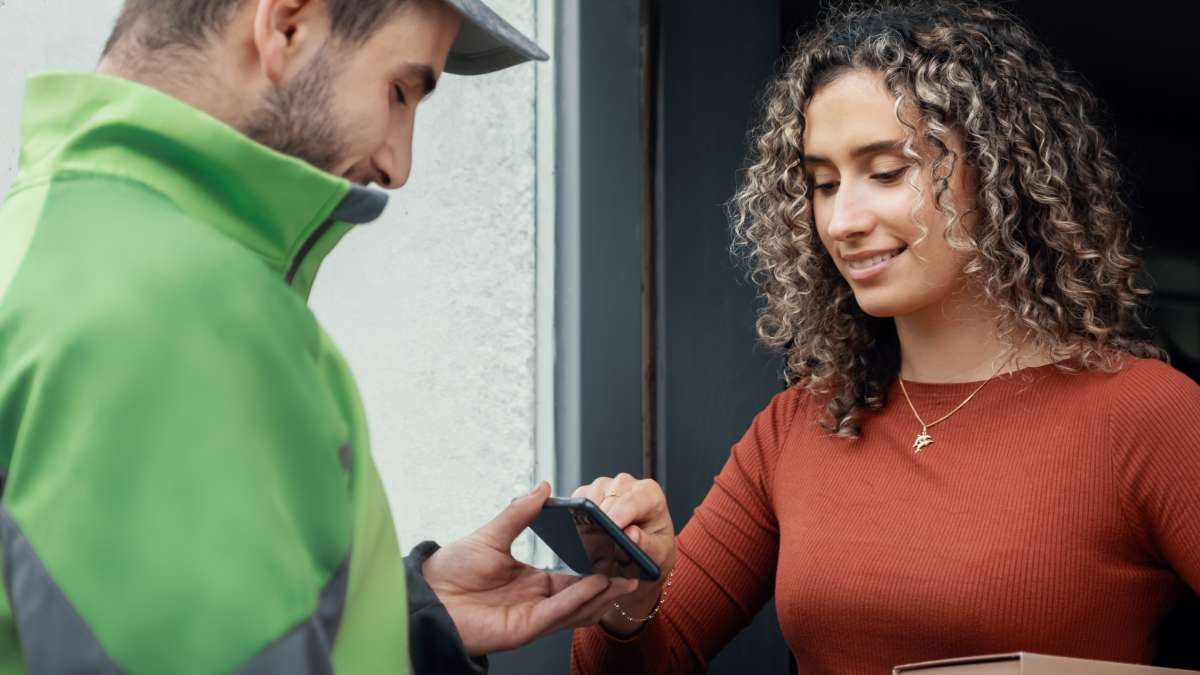 En kvinne som signerer på mobiltelefonen til en Bring-sjåfør