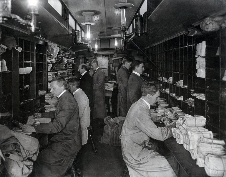 Postmenn sorterer post ombord på tog i 1914.