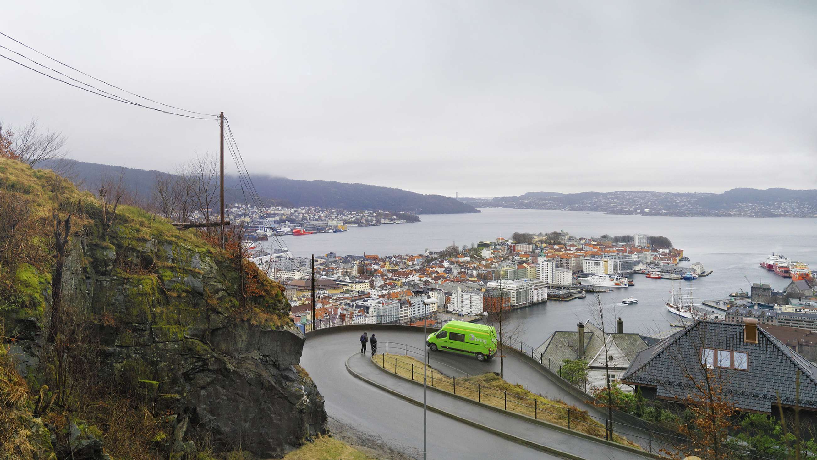 En Bring-bil på vei opp en bakke med utsikt over en by og fjord i bakgrunnen