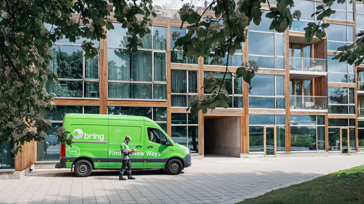 En elektrisk Bring-bil parkert foran en moderne bygning