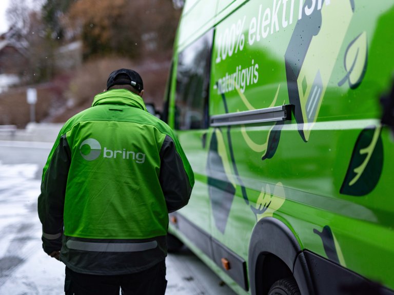 Ryggen til Bring-bud på vei inn i bilen.