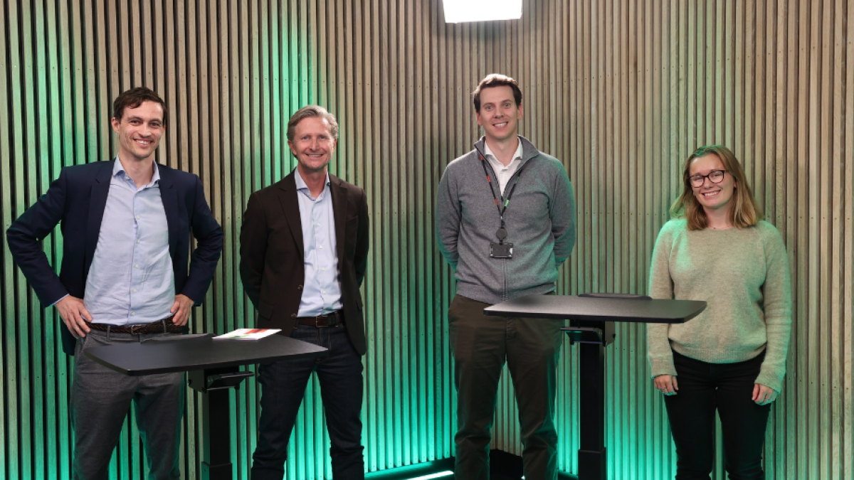 Tre menn og en dame foran en vegg