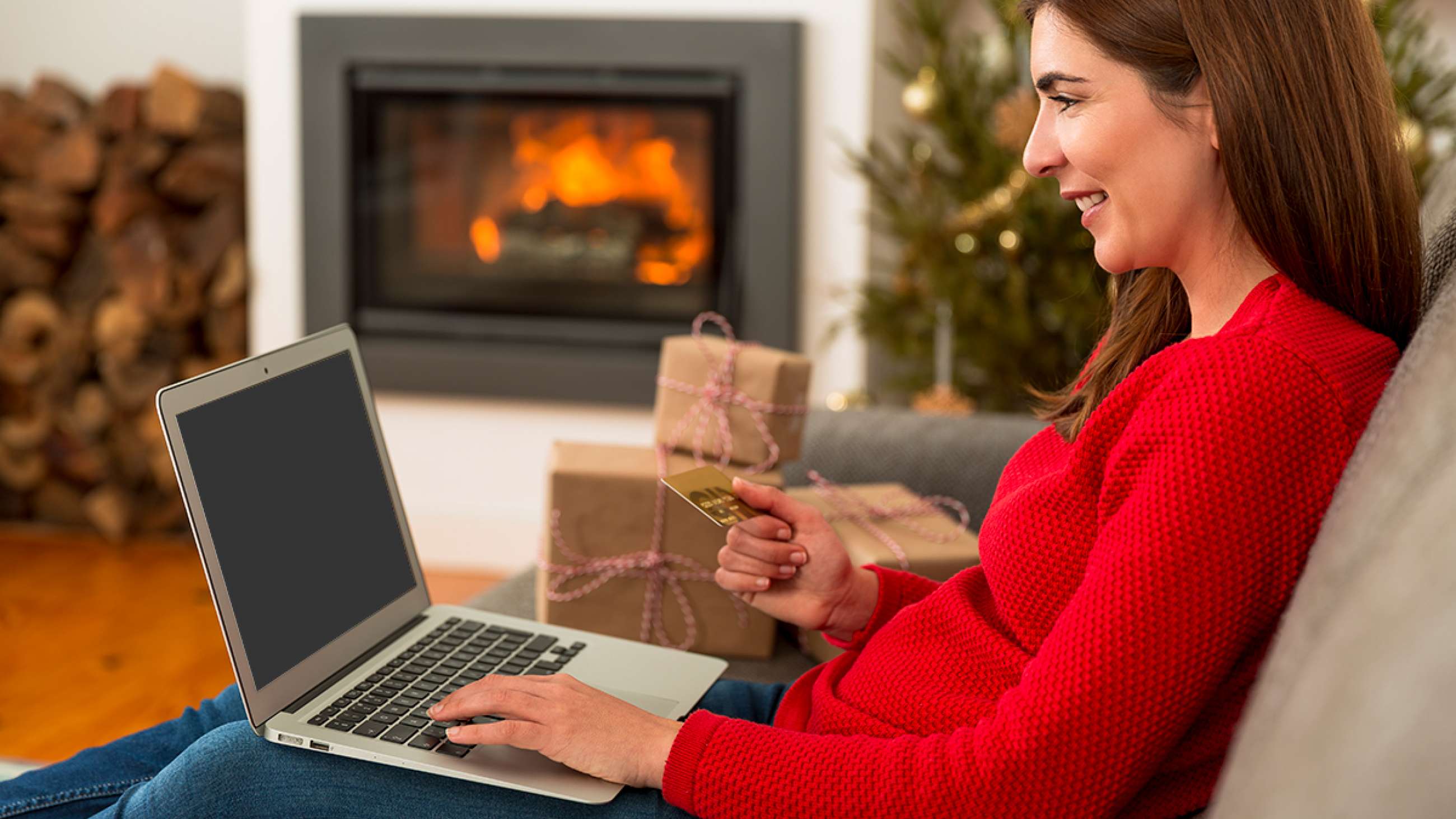 Kvinne julehandler på nett, med bankkort i hånden.