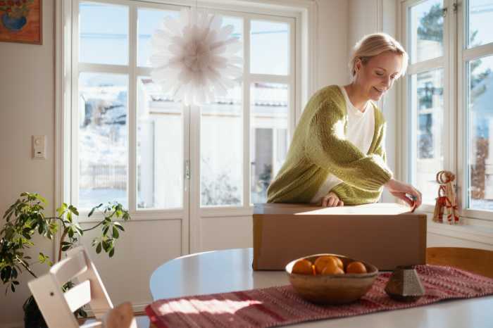 En kvinne står med en pakke på et bord foran seg