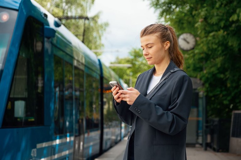 Jente på mobilen ved siden av trikk