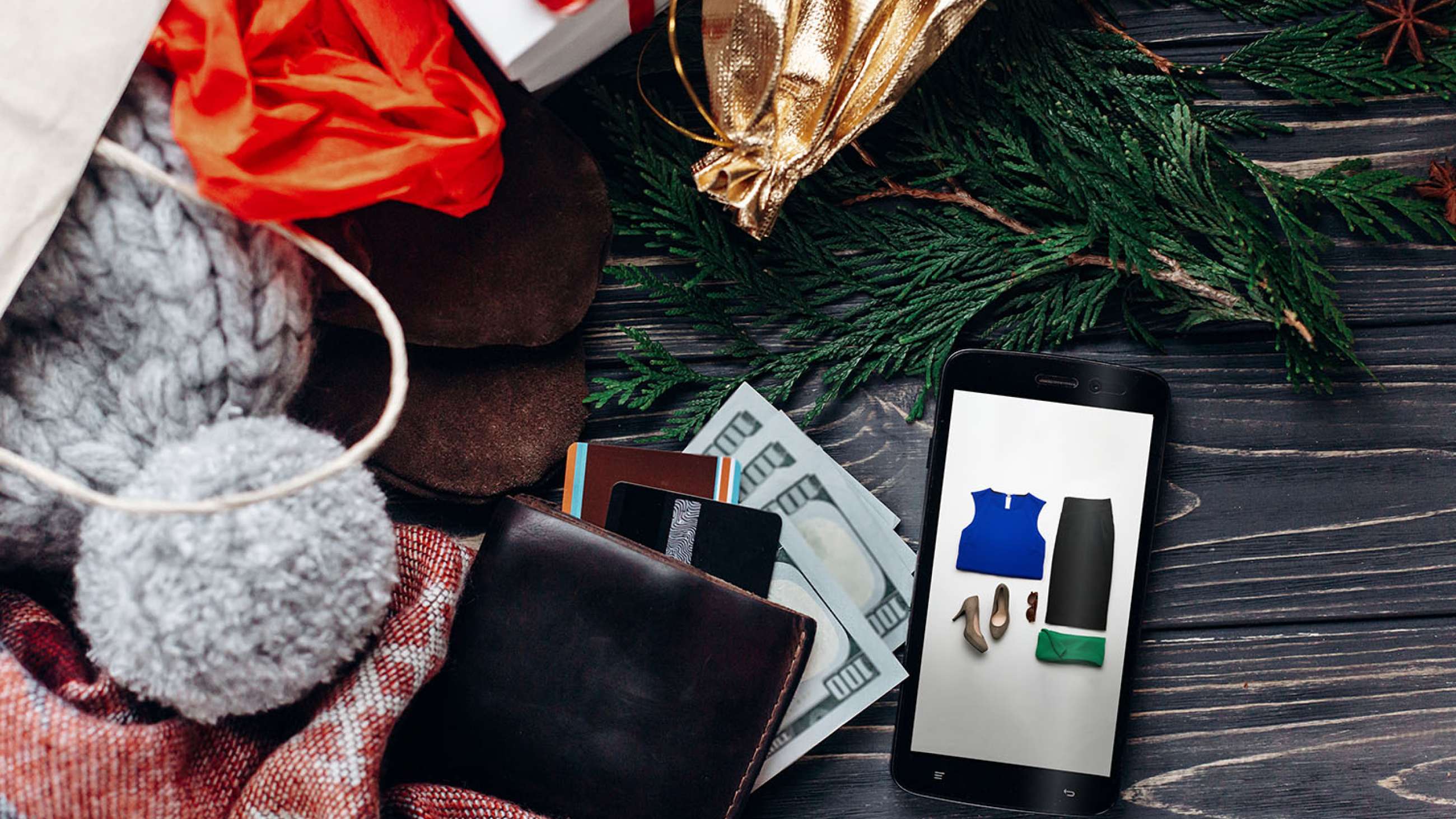 Julegaver som lommebok, kort, mobil og lue ligger på et bord.