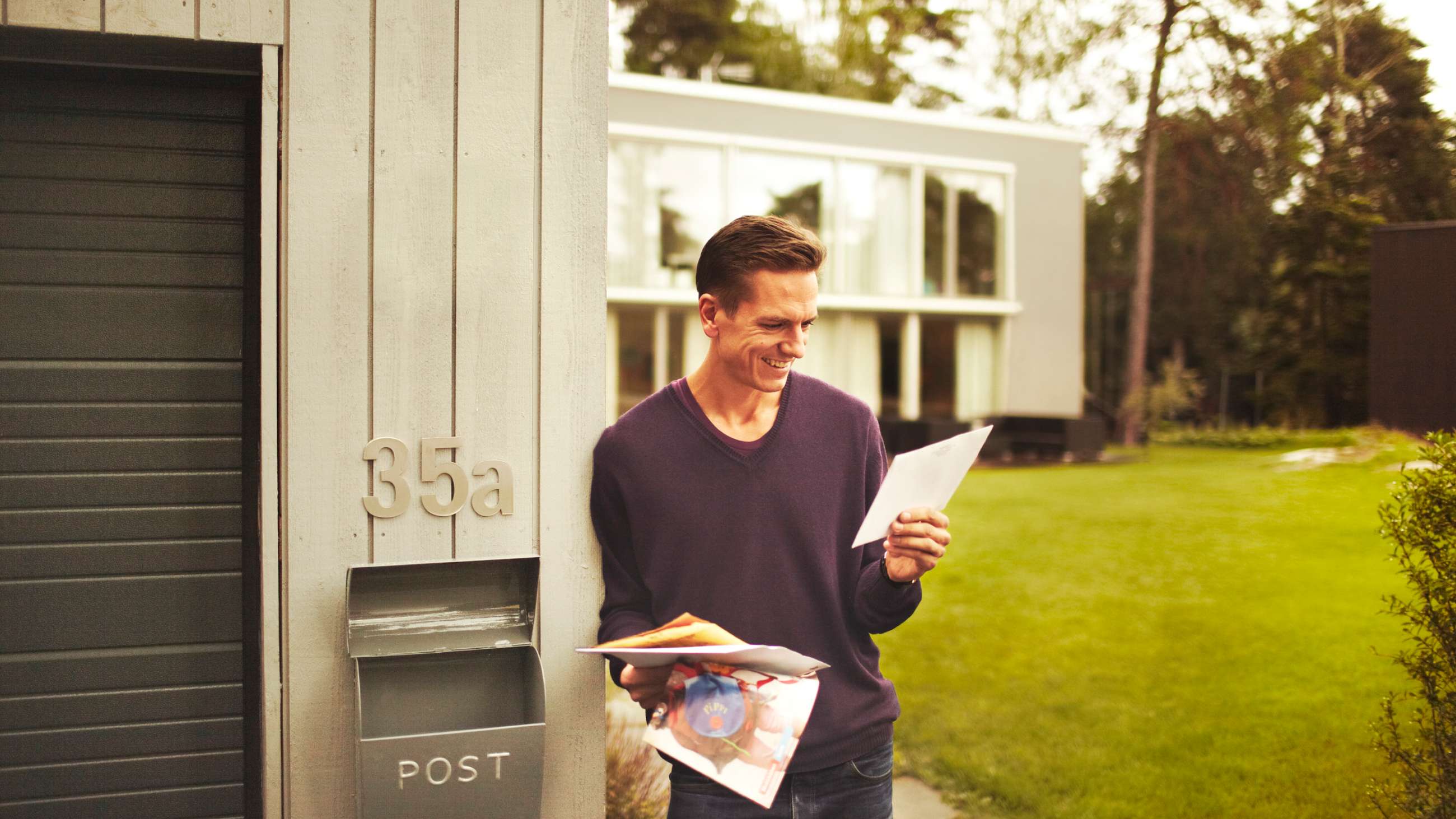 En mann som står ved siden av en postkasse og ser på reklamene han har fått