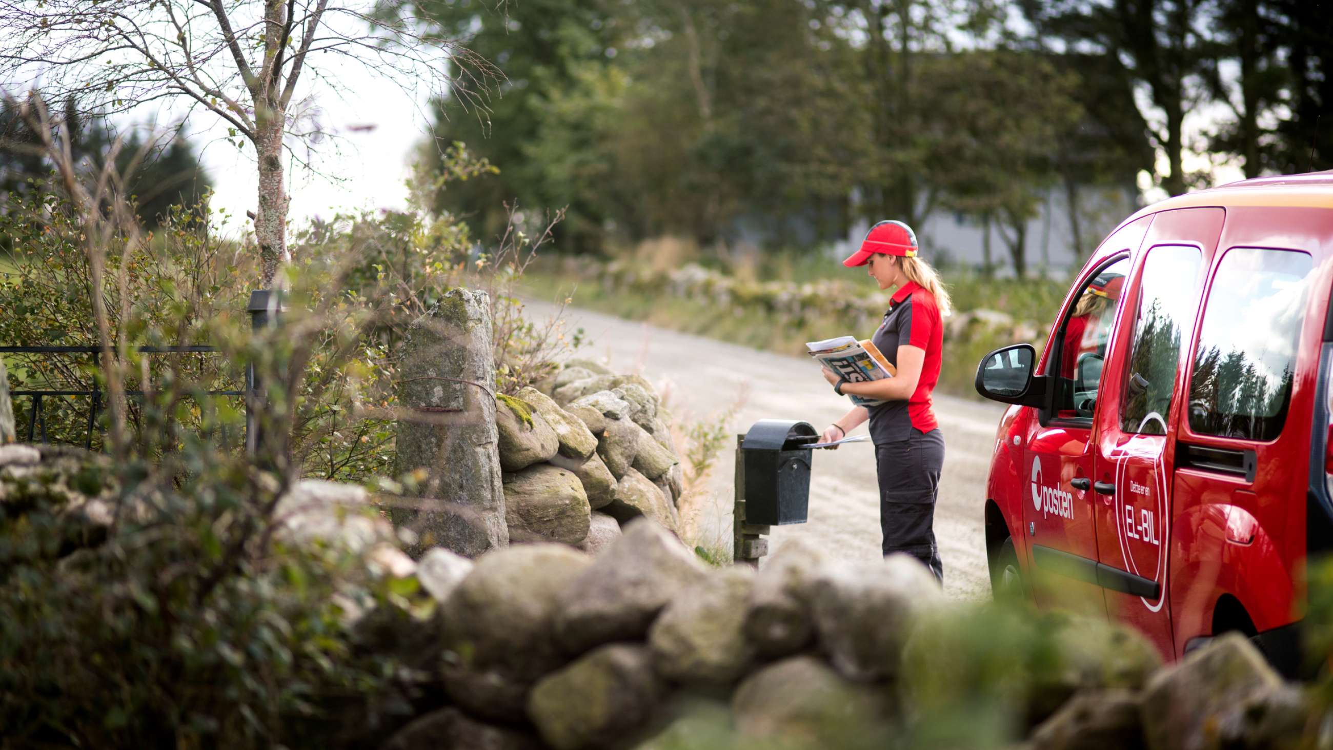 Postbud som leverer post i en svart postkasse