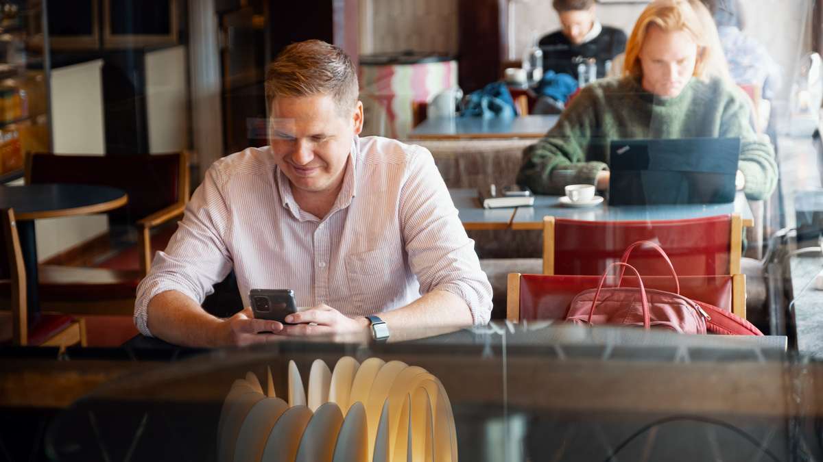 Mann smiler til telefonen