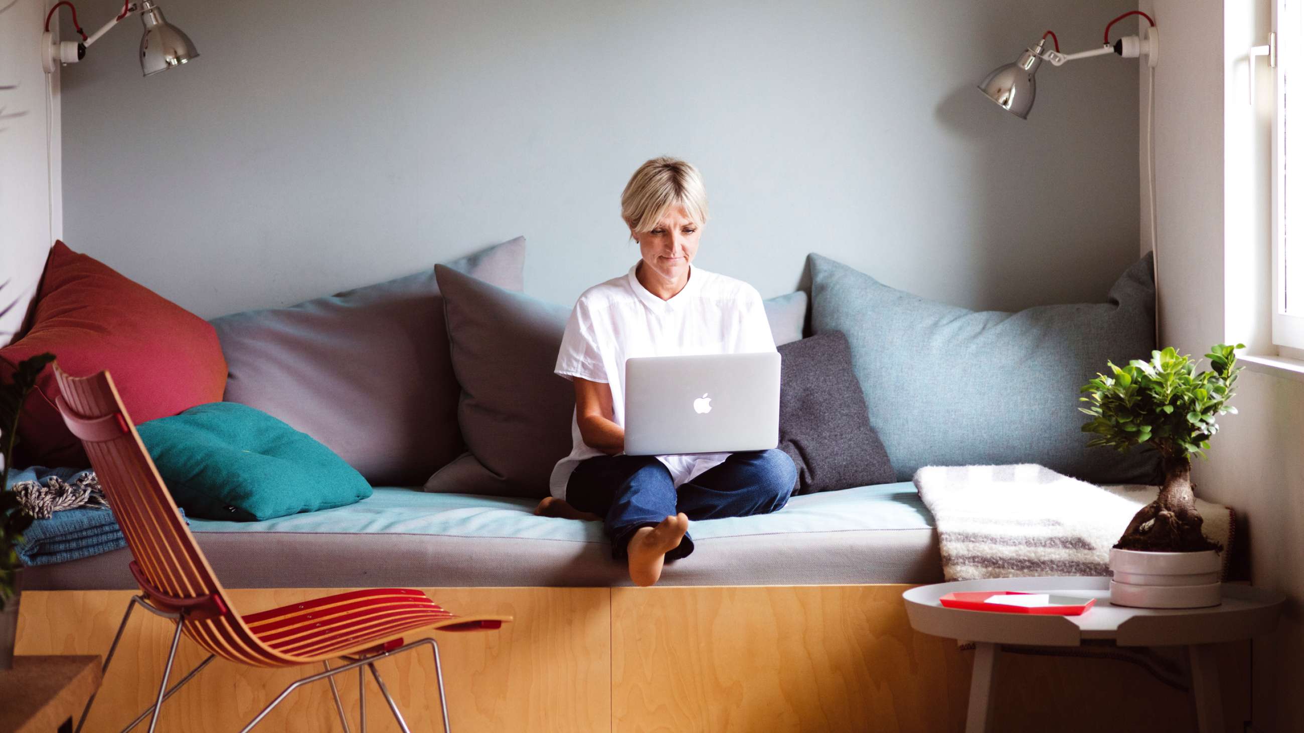 En kvinne som sitter på en sofa med en laptop på fanget