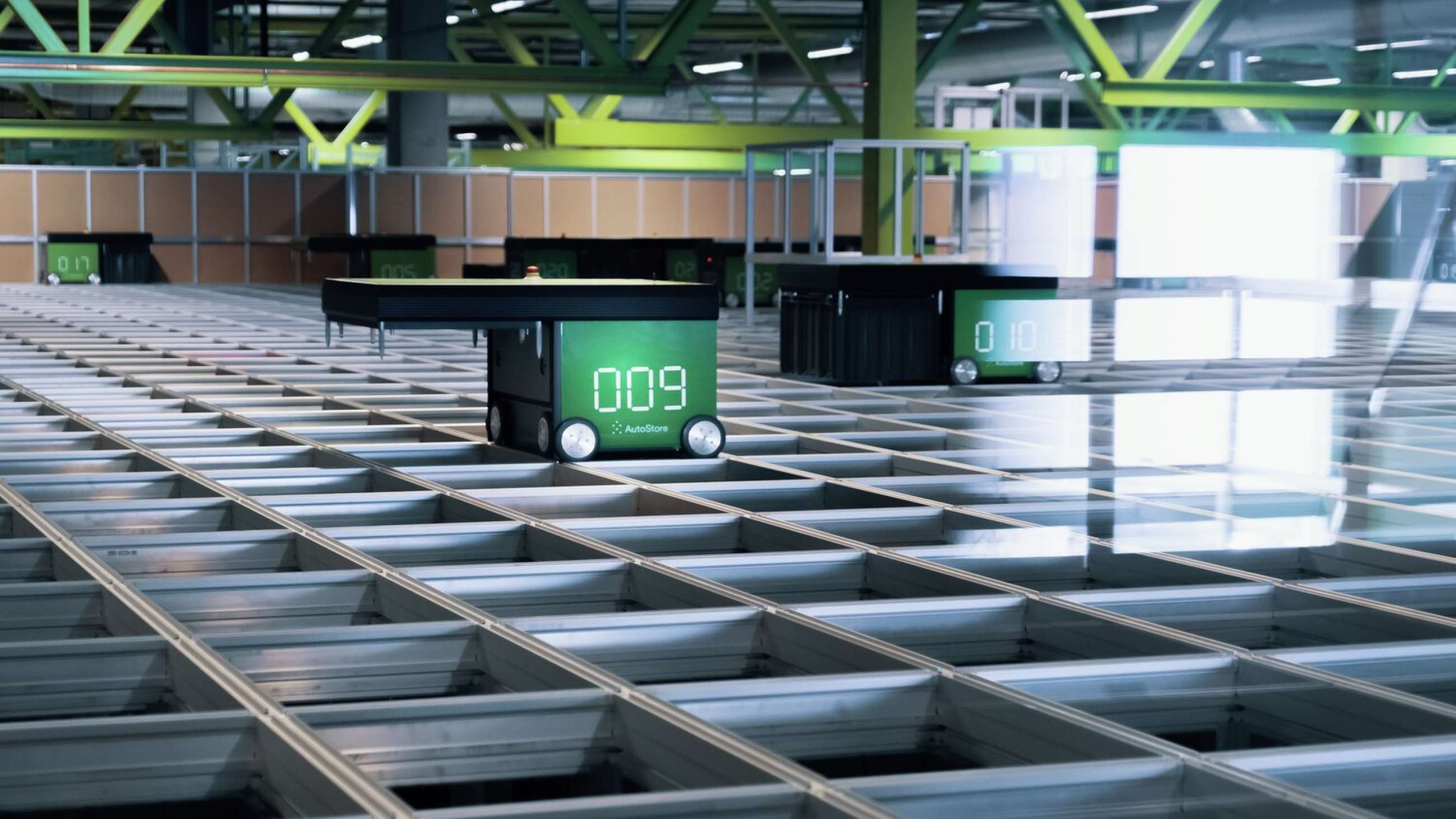 Autostore lager der en grønn robot kjører på lageret. 