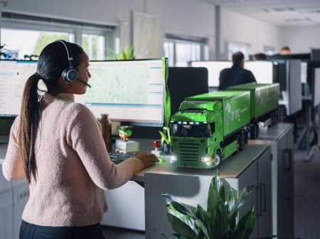 En ansatt i Bring kundeservice står foran en datamaskin med headset på hodet