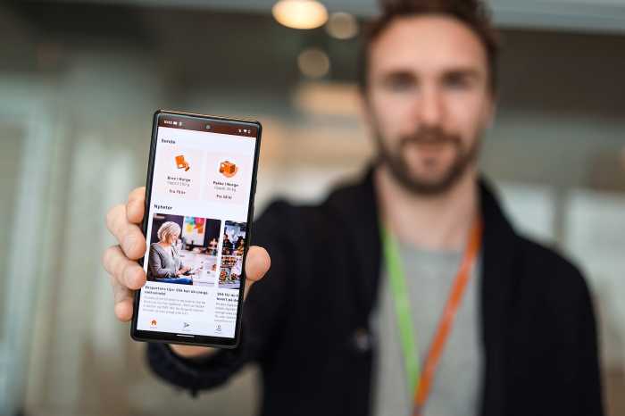 Mann som holder en telefon som viser Posten-appen.