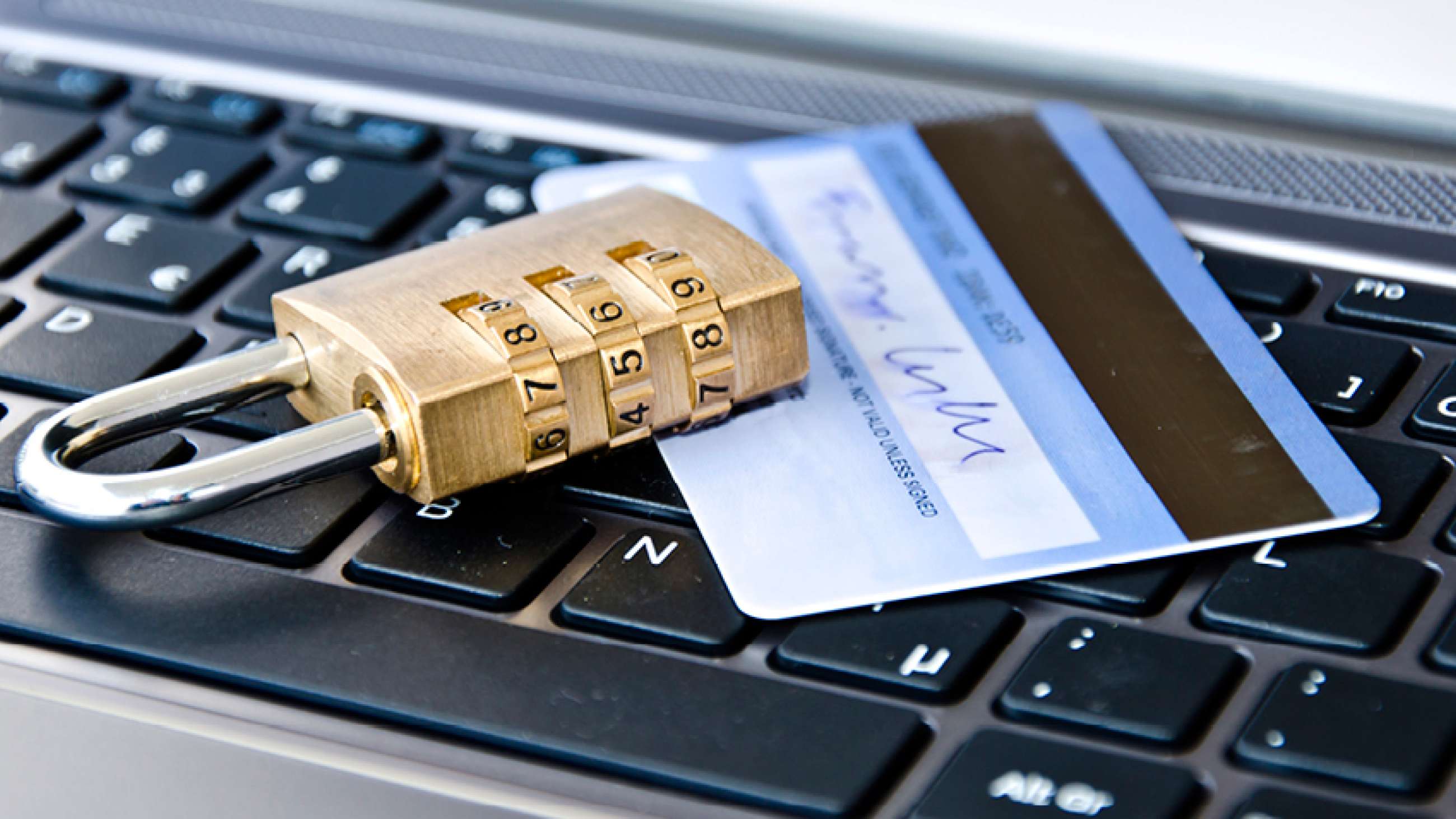 En hengelås og et kredittkort som ligger på et laptoptastatur