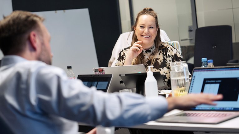 Trendanalytiker Vikki Walle-Hansen sitter smilende ved en datamaskin rundt et møtebord, fra jurymøtet til Netthandelsprisene. I forgrunnen ses ryggen til en mann i skjorte.