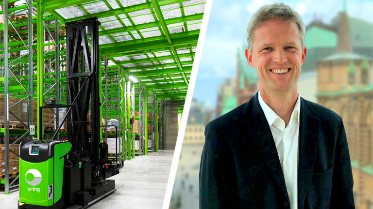 Grønn lagerrobot til venstre i bilde, Tobias Neumann i mørk dressjakke og hvit skjorte til høyre.