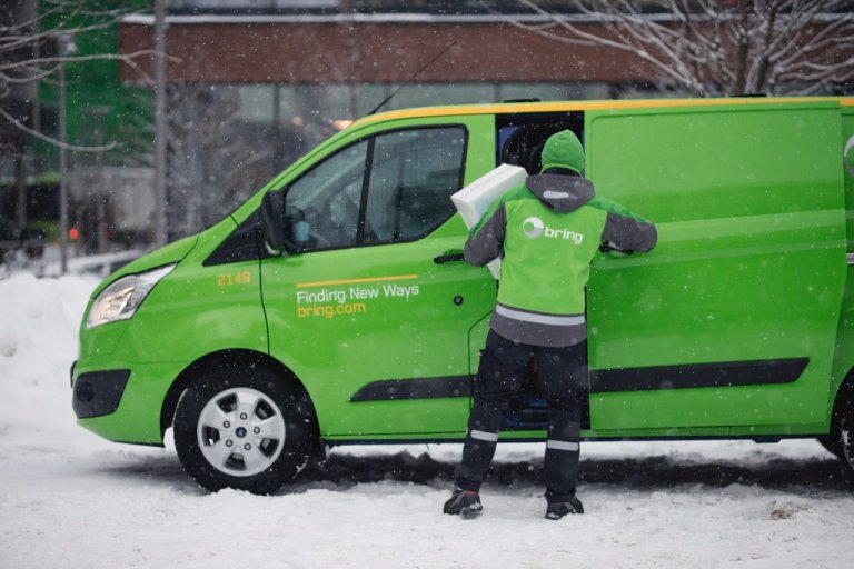 Bring-sjåfør tar ut pakker fra varebil. Vinterbilde.