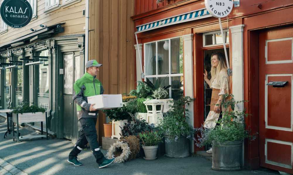 Bringbud leverer pakke til dame i blomsterbutikk