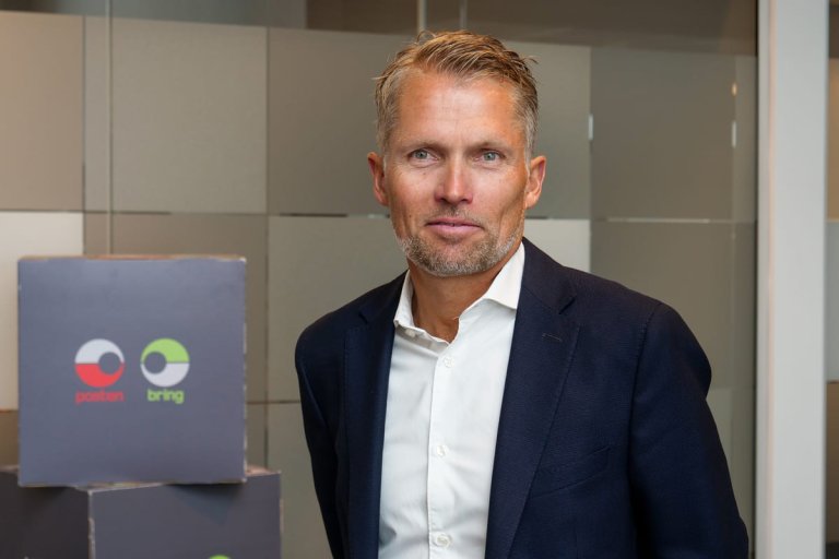 Mann i dress foran glassvegg