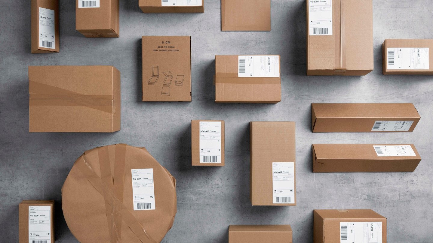 Pakker i gråpapir  i ulike format ligger spredd utover et grått gulv.