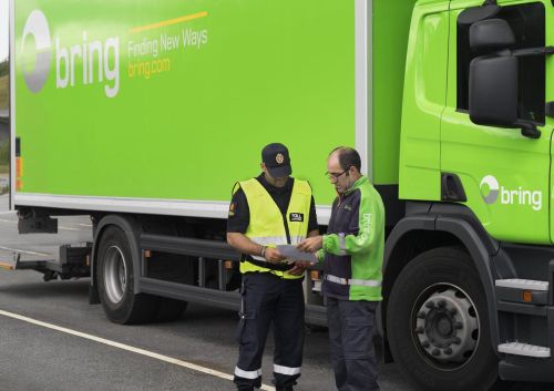 Bring sjåfør og tollkontrollør snakker sammen foran en Bring lastebil.